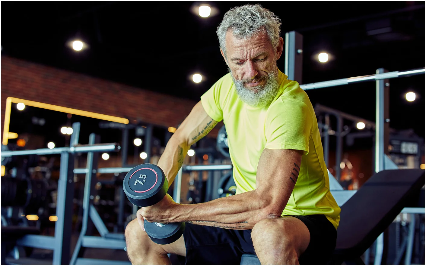 weight workout focused mature man in sportswear lifting heavy dumbbells and pumping his biceps while training at gym 283254 1